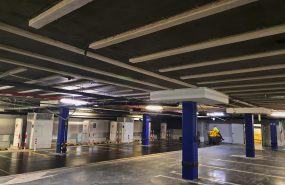 CH Alfa Centrum Białystok. Wzmocnienie stropu żelbetowego nad parkingiem podziemnym o dopuszczalnym obciążeniu użytkowym 5kN/m2 do wymaganego 10kN/m2. Na zdjęciu widoczne wzmocnienia taśmami stalowymi i dodatkowe głowice przy słupach.
