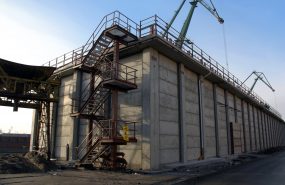 Magazyn tlenku glinu Port Gdynia. Konstrukcja główna żelbetowa w postaci słupów wspornikowych o wysokości ścian 10 metrów. Ściany wykonane w postaci płyt prefabrykowanych wsuniętych od góry pomiędzy słupami.